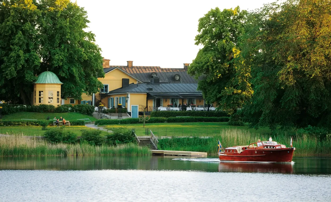 The yellow inn of Stallmästaregården by the water at Brunnsviken, with a classic wooden boat